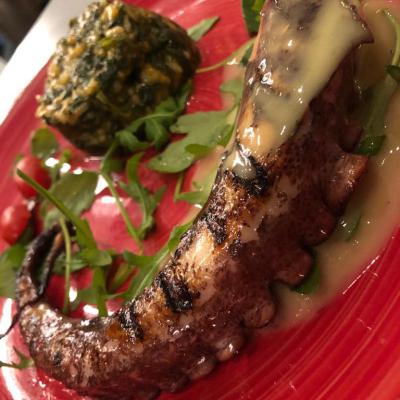 Octopus vom Grill auf gedünstetem Baby-Blattspinat mit einer Olivenöl-Zitronen-Vinaigrette. Octopus Vom Grill Auf Gedunstetem Baby Blattspinat Mit Einer Olivenol Zitrone Vinaigrette